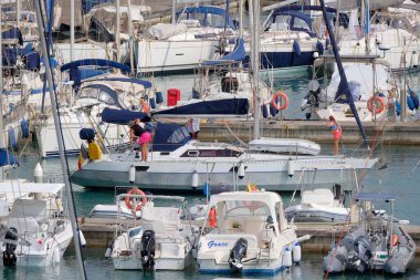 İtalya, Sicilya, Akdeniz, Marina di Ragusa (Ragusa ili); 18 Temmuz 2025, limandaki bir yelkenli teknesinde insanlar - EDITORIAL