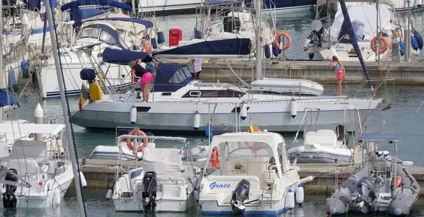 İtalya, Sicilya, Akdeniz, Marina di Ragusa (Ragusa ili); 18 Temmuz 2025, limandaki bir yelkenli teknesinde insanlar - EDITORIAL