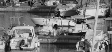 İtalya, Sicilya, Akdeniz, Marina di Ragusa (Ragusa Eyaleti); 19 Temmuz 2025, limandaki bir motorlu tekne ve lüks yatlarda adam - EDITORIAL