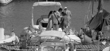 İtalya, Sicilya, Akdeniz, Marina di Ragusa (Ragusa Eyaleti); 20 Temmuz 2025, limandaki büyük bir kauçuk teknede insanlar - EDITORIAL