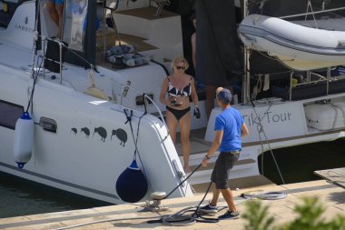 İtalya, Sicilya, Akdeniz, Marina di Ragusa (Ragusa Eyaleti); 22 Temmuz 2025, limandaki katamaran yelkenli teknesinde insanlar - EDITORIAL