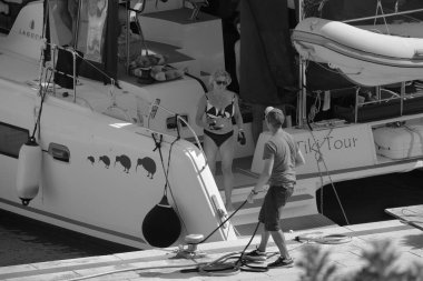 İtalya, Sicilya, Akdeniz, Marina di Ragusa (Ragusa Eyaleti); 22 Temmuz 2025, limandaki katamaran yelkenli teknesinde insanlar - EDITORIAL