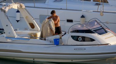 İtalya, Sicilya, Akdeniz, Marina di Ragusa (Ragusa Eyaleti); 23 Temmuz 2025, limandaki büyük bir lastik teknede adam - EDITORIAL