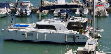 İtalya, Sicilya, Akdeniz, Marina di Ragusa (Ragusa Eyaleti); 25 Temmuz 2025, limandaki katamaran yelkenli teknesinde insanlar - EDITORIAL