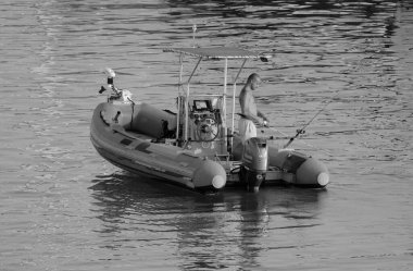 İtalya, Sicilya, Akdeniz, Marina di Ragusa (Ragusa ili); 25 Temmuz 2025, limanda kauçuk bir teknede balık tutan çift - EDITORIAL