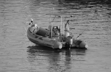 İtalya, Sicilya, Akdeniz, Marina di Ragusa (Ragusa ili); 25 Temmuz 2025, limanda kauçuk bir teknede balık tutan çift - EDITORIAL