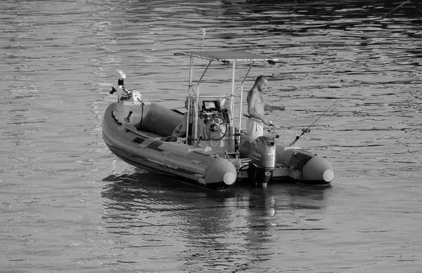 İtalya, Sicilya, Akdeniz, Marina di Ragusa (Ragusa ili); 25 Temmuz 2025, limanda kauçuk bir teknede balık tutan çift - EDITORIAL