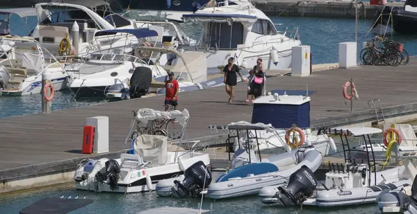 İtalya, Sicilya, Akdeniz, Marina di Ragusa (Ragusa ili); 4 Ağustos 2025, limandaki insanlar, motorlu tekneler ve lüks yatlar - EDITORIAL