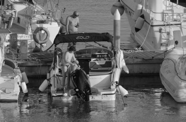 İtalya, Sicilya, Akdeniz, Marina di Ragusa (Ragusa ili); 7 Ağustos 2025, limandaki bir motorlu tekne ve lüks yatlarda yaşayan insanlar - EDITORIAL