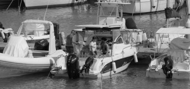 İtalya, Sicilya, Akdeniz, Marina di Ragusa (Ragusa ili); 9 Ağustos 2025, limandaki bir motorlu tekne ve lüks yatlarda yaşayan insanlar - EDITORIAL