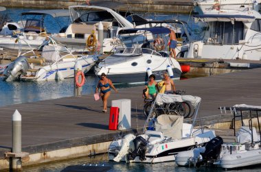 İtalya, Sicilya, Akdeniz, Marina di Ragusa (Ragusa ili); 9 Ağustos 2025, limandaki insanlar, motorlu tekneler ve lüks yatlar - EDITORIAL