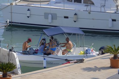 İtalya, Sicilya, Akdeniz, Marina di Ragusa (Ragusa ili); 10 Ağustos 2025, limandaki bir motorlu tekne ve lüks yatlarda yaşayan insanlar - EDITORIAL