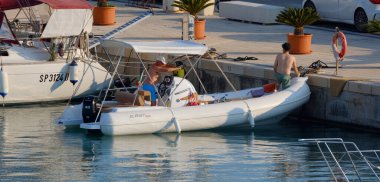 İtalya, Sicilya, Akdeniz, Marina di Ragusa (Ragusa ili); 10 Ağustos 2025, limandaki kauçuk bir teknede erkekler - EDITORIAL