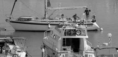 İtalya, Sicilya, Akdeniz, Marina di Ragusa (Ragusa Eyaleti); 11 Ağustos 2025, limandaki bir yelkenli ve lüks yatlarda yaşayan insanlar - EDITORIAL