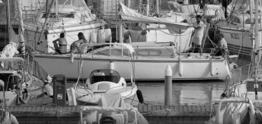 İtalya, Sicilya, Akdeniz, Marina di Ragusa (Ragusa ili); 21 Ağustos 2025, limandaki bir yelkenli teknesinde insanlar - EDITORIAL