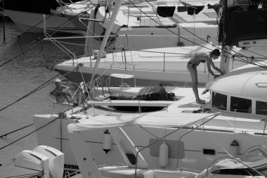 İtalya, Sicilya, Akdeniz, Marina di Ragusa (Ragusa ili); 22 Ağustos 2025, oğlu ile birlikte limandaki katamaran yelkenli teknesinde bir kadın - EDITORIAL