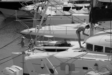 İtalya, Sicilya, Akdeniz, Marina di Ragusa (Ragusa ili); 22 Ağustos 2025, oğlu ile birlikte limandaki katamaran yelkenli teknesinde bir kadın - EDITORIAL