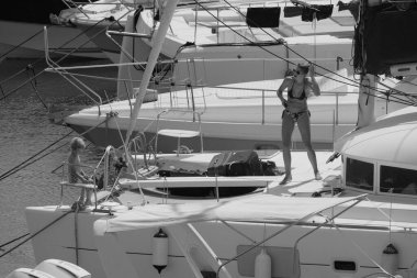 İtalya, Sicilya, Akdeniz, Marina di Ragusa (Ragusa ili); 22 Ağustos 2025, oğlu ile birlikte limandaki katamaran yelkenli teknesinde bir kadın - EDITORIAL