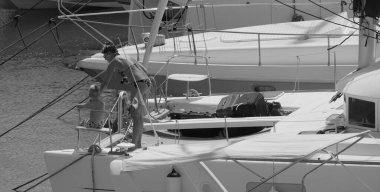 İtalya, Sicilya, Akdeniz, Marina di Ragusa (Ragusa ili); 22 Ağustos 2025, oğlu ile birlikte limandaki katamaran yelkenli teknesinde bir kadın - EDITORIAL