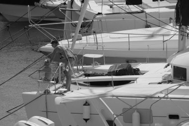 İtalya, Sicilya, Akdeniz, Marina di Ragusa (Ragusa ili); 22 Ağustos 2025, oğlu ile birlikte limandaki katamaran yelkenli teknesinde bir kadın - EDITORIAL