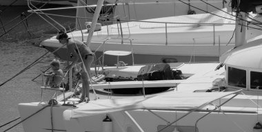 İtalya, Sicilya, Akdeniz, Marina di Ragusa (Ragusa ili); 22 Ağustos 2025, oğlu ile birlikte limandaki katamaran yelkenli teknesinde bir kadın - EDITORIAL