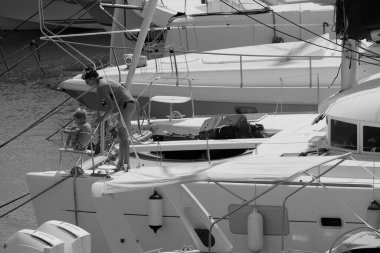 İtalya, Sicilya, Akdeniz, Marina di Ragusa (Ragusa ili); 22 Ağustos 2025, oğlu ile birlikte limandaki katamaran yelkenli teknesinde bir kadın - EDITORIAL