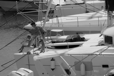 İtalya, Sicilya, Akdeniz, Marina di Ragusa (Ragusa ili); 22 Ağustos 2025, oğlu ile birlikte limandaki katamaran yelkenli teknesinde bir kadın - EDITORIAL