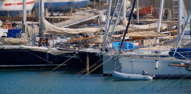 İtalya, Sicilya, Akdeniz, Marina di Ragusa (Ragusa Eyaleti); 24 Ağustos 2025, limandaki bir yelkenli ve lüks yatlarda adam - EDITORIAL