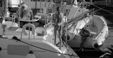 İtalya, Sicilya, Akdeniz, Marina di Ragusa (Ragusa ili); 24 Ağustos 2025, oğlu ile birlikte limanda katamaran yelkenli teknesinde bir kadın - EDITORIAL