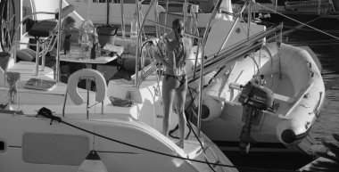 İtalya, Sicilya, Akdeniz, Marina di Ragusa (Ragusa ili); 24 Ağustos 2025, oğlu ile birlikte limanda katamaran yelkenli teknesinde bir kadın - EDITORIAL