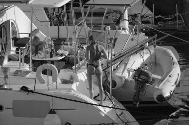 İtalya, Sicilya, Akdeniz, Marina di Ragusa (Ragusa ili); 24 Ağustos 2025, oğlu ile birlikte limanda katamaran yelkenli teknesinde bir kadın - EDITORIAL