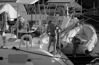 İtalya, Sicilya, Akdeniz, Marina di Ragusa (Ragusa ili); 24 Ağustos 2025, oğlu ile birlikte limanda katamaran yelkenli teknesinde bir kadın - EDITORIAL