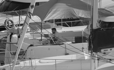 İtalya, Sicilya, Akdeniz, Marina di Ragusa (Ragusa Eyaleti); 25 Ağustos 2025, limandaki katamaran yelkenli teknesinde dizüstü bilgisayarı olan adam - EDITORIAL