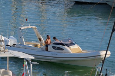 İtalya, Sicilya, Akdeniz, Marina di Ragusa (Ragusa ili); 25 Ağustos 2025, limandaki büyük lastik bir teknede köpeği olan insanlar - EDITORIAL