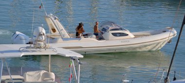 İtalya, Sicilya, Akdeniz, Marina di Ragusa (Ragusa ili); 25 Ağustos 2025, limandaki büyük lastik bir teknede köpeği olan insanlar - EDITORIAL