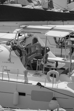 İtalya, Sicilya, Akdeniz, Marina di Ragusa (Ragusa ili); 26 Ağustos 2025, oğlu ile birlikte limandaki katamaran yelkenli teknesinde bir kadın - EDITORIAL