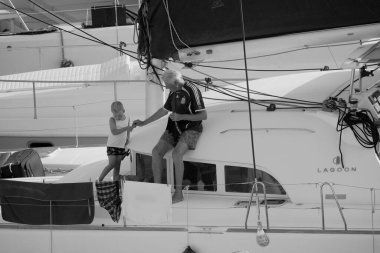 İtalya, Sicilya, Akdeniz, Marina di Ragusa (Ragusa Eyaleti); 26 Ağustos 2025, küçük oğluyla birlikte limanda bir katamaran yelkenli teknesinde