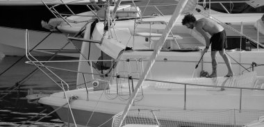 İtalya, Sicilya, Akdeniz, Marina di Ragusa (Ragusa ili); 30 Ağustos 2025; limanda lüks bir yatı temizleyen adam - EDITORIAL