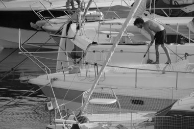 İtalya, Sicilya, Akdeniz, Marina di Ragusa (Ragusa ili); 30 Ağustos 2025; limanda lüks bir yatı temizleyen adam - EDITORIAL