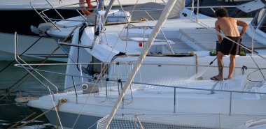 İtalya, Sicilya, Akdeniz, Marina di Ragusa (Ragusa ili); 30 Ağustos 2025; limanda lüks bir yatı temizleyen adam - EDITORIAL