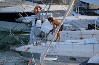 İtalya, Sicilya, Akdeniz, Marina di Ragusa (Ragusa ili); 30 Ağustos 2025; limanda lüks bir yatı temizleyen adam - EDITORIAL