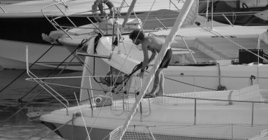 İtalya, Sicilya, Akdeniz, Marina di Ragusa (Ragusa ili); 30 Ağustos 2025; limanda lüks bir yatı temizleyen adam - EDITORIAL