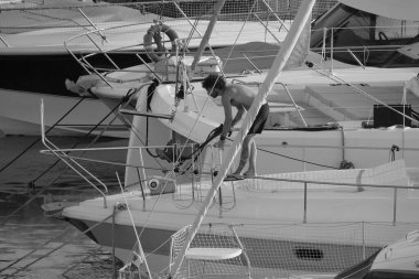 İtalya, Sicilya, Akdeniz, Marina di Ragusa (Ragusa ili); 30 Ağustos 2025; limanda lüks bir yatı temizleyen adam - EDITORIAL