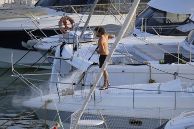 İtalya, Sicilya, Akdeniz, Marina di Ragusa (Ragusa ili); 30 Ağustos 2025; limanda lüks bir yatı temizleyen adam - EDITORIAL