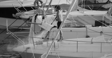 İtalya, Sicilya, Akdeniz, Marina di Ragusa (Ragusa ili); 30 Ağustos 2025; limanda lüks bir yatı temizleyen adam - EDITORIAL