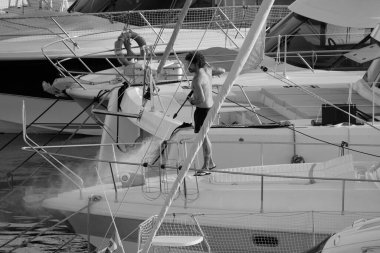 İtalya, Sicilya, Akdeniz, Marina di Ragusa (Ragusa ili); 30 Ağustos 2025; limanda lüks bir yatı temizleyen adam - EDITORIAL