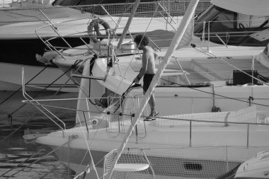 İtalya, Sicilya, Akdeniz, Marina di Ragusa (Ragusa ili); 30 Ağustos 2025; limanda lüks bir yatı temizleyen adam - EDITORIAL