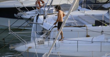 İtalya, Sicilya, Akdeniz, Marina di Ragusa (Ragusa ili); 30 Ağustos 2025; limanda lüks bir yatı temizleyen adam - EDITORIAL