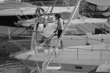 İtalya, Sicilya, Akdeniz, Marina di Ragusa (Ragusa ili); 30 Ağustos 2025; limanda lüks bir yatı temizleyen adam - EDITORIAL