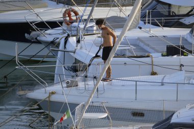 İtalya, Sicilya, Akdeniz, Marina di Ragusa (Ragusa ili); 30 Ağustos 2025; limanda lüks bir yatı temizleyen adam - EDITORIAL